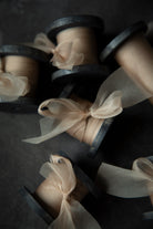 Spools of beige ribbon tied into bows on dark wooden spools.
