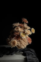 Bouquet of blush flowers in a glass vase on a dark background