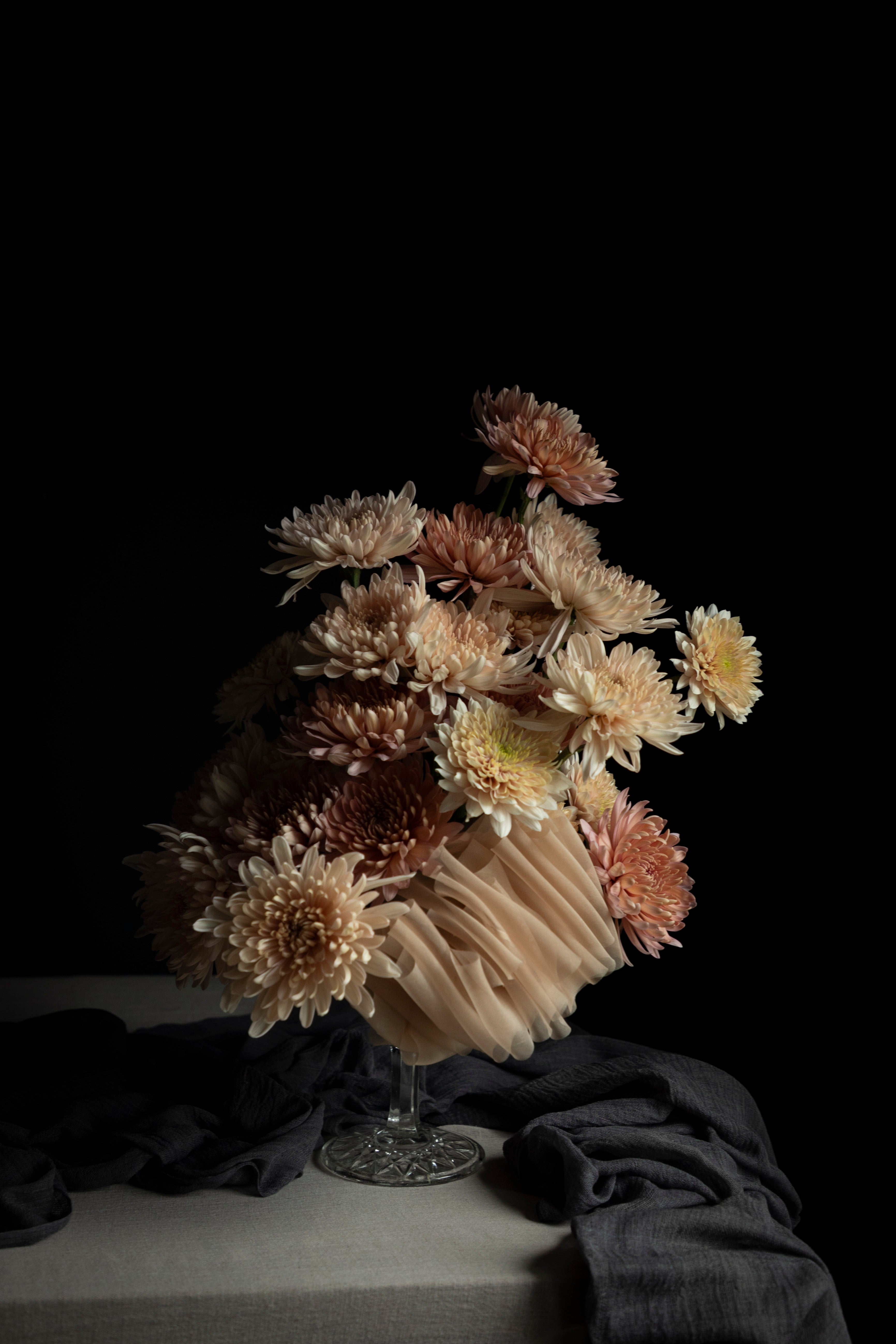 Bouquet of blush flowers in a glass vase on a dark background