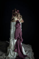 Decorative cake with floral arrangement and plum noir silk ribbon against a dark background