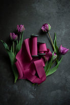 hot pink silk ribbon on a moody black background with purple tulip flowers