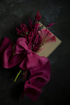 gift wrapped with hot pink silk ribbon and topped with dried floral arrangement