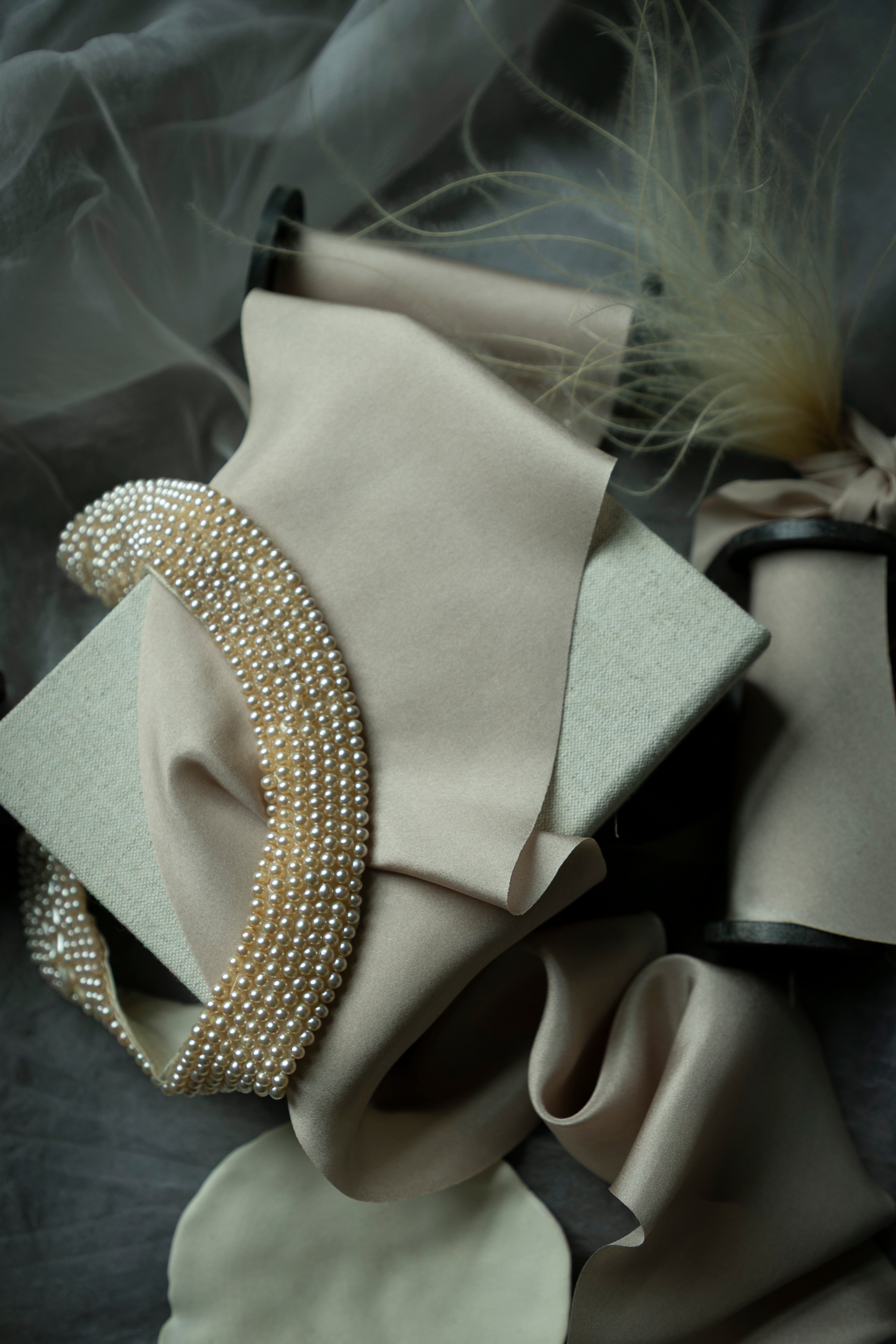 Pearl-colored silk ribbon on display with vintage pearls and feathers