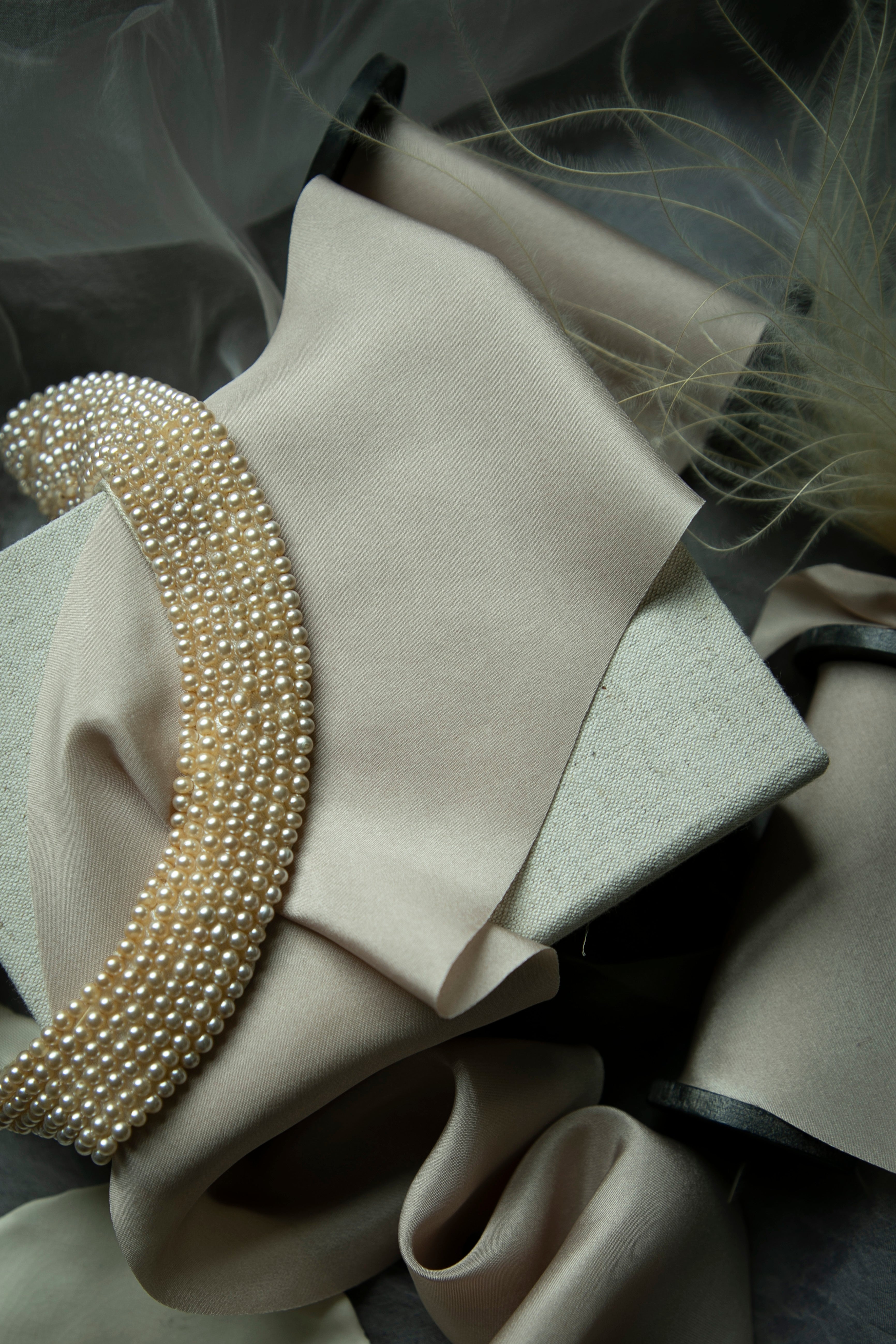 Close-up of pearl-colored silk ribbon with a pearl-like trim on a dark background