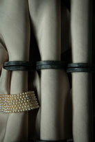 Close-up of beige ribbon on vintage wood spools paired with a vintage pearl necklace.