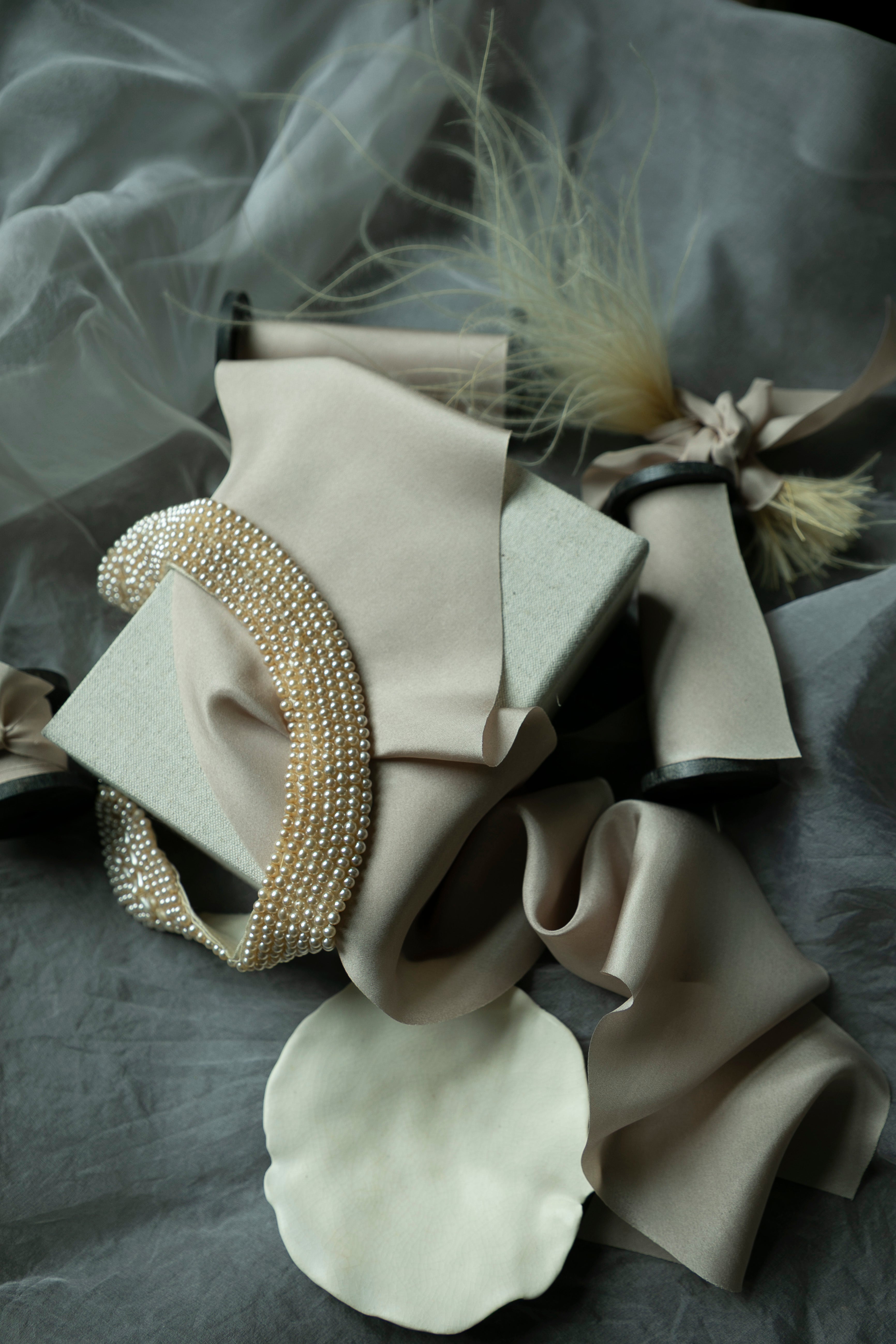 Decorative headband with pearls and feathers on a gray fabric background