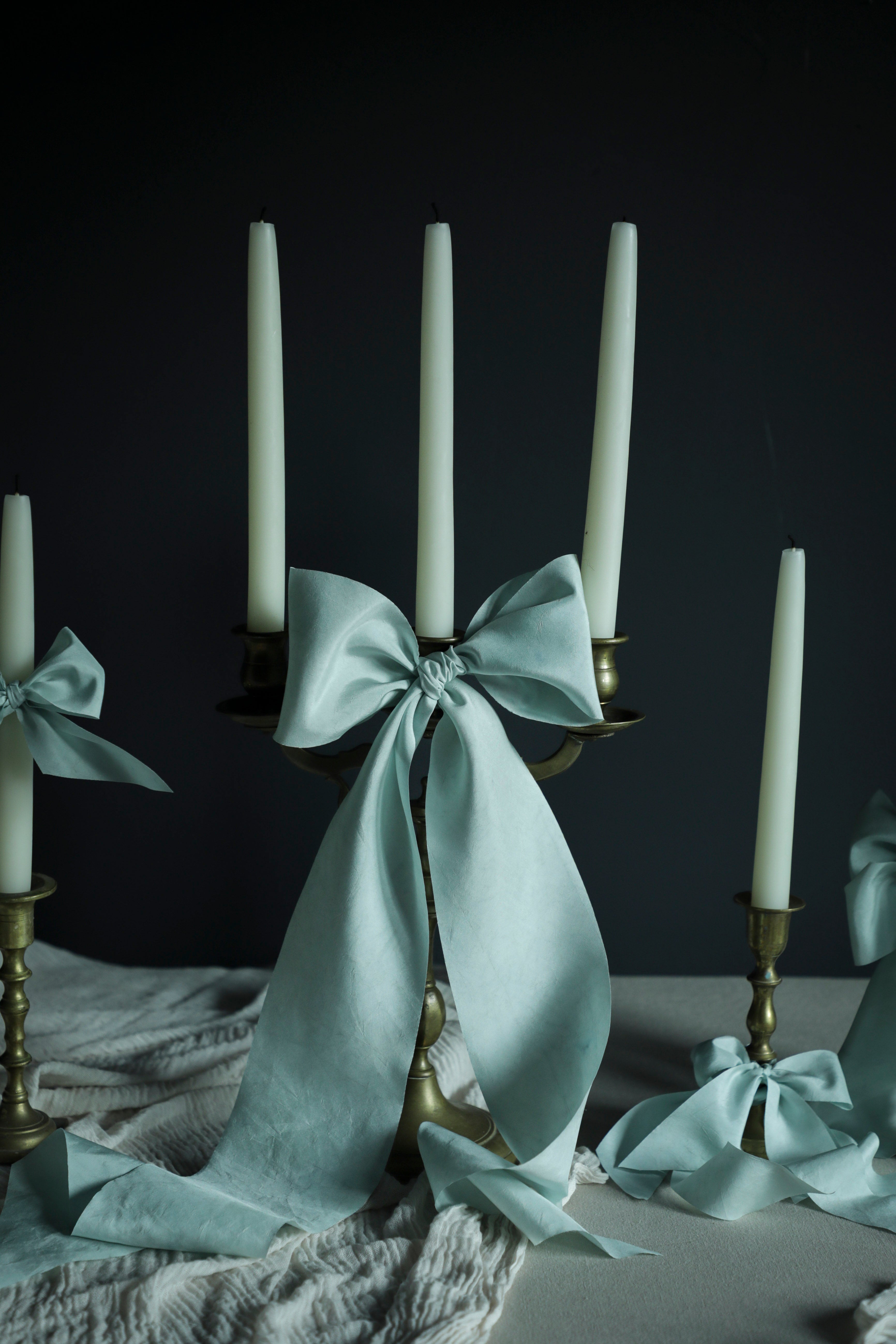 Candle holder with a baby blue bow and candles on a dark background