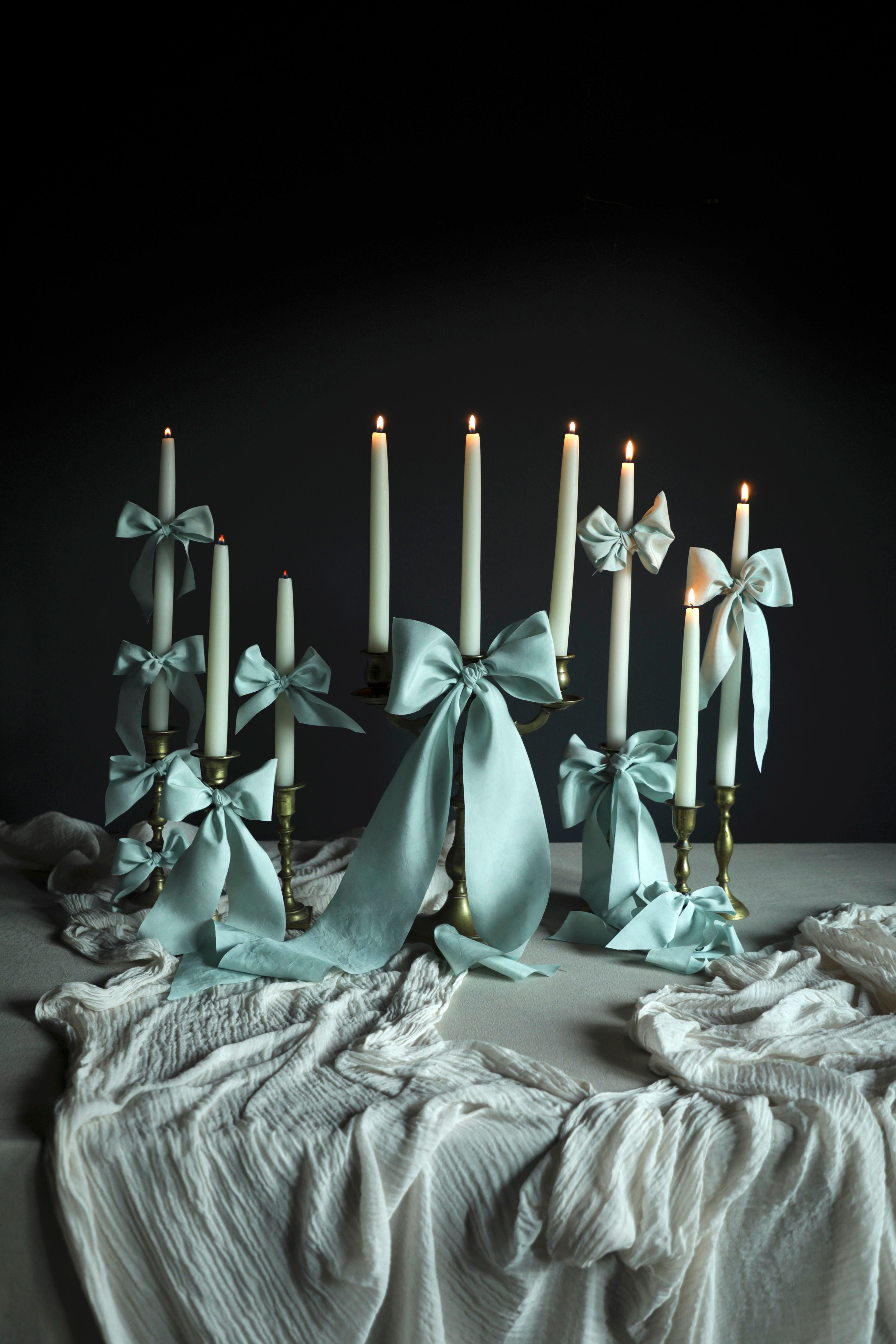 Table centerpiece decor with Candlesticks with light blue ribbons on a dark background