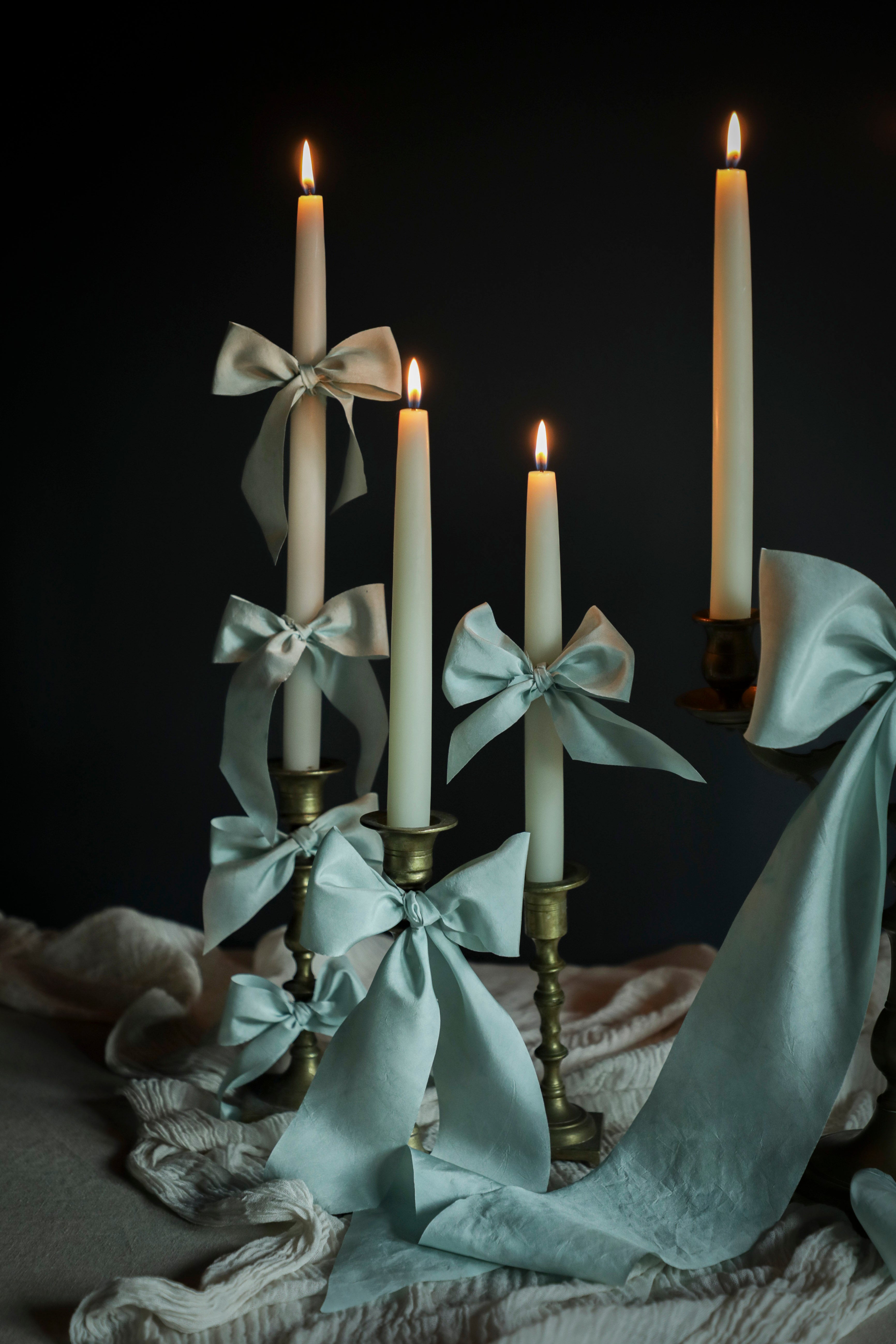 Candlesticks with light blue ribbons and candles against a dark background