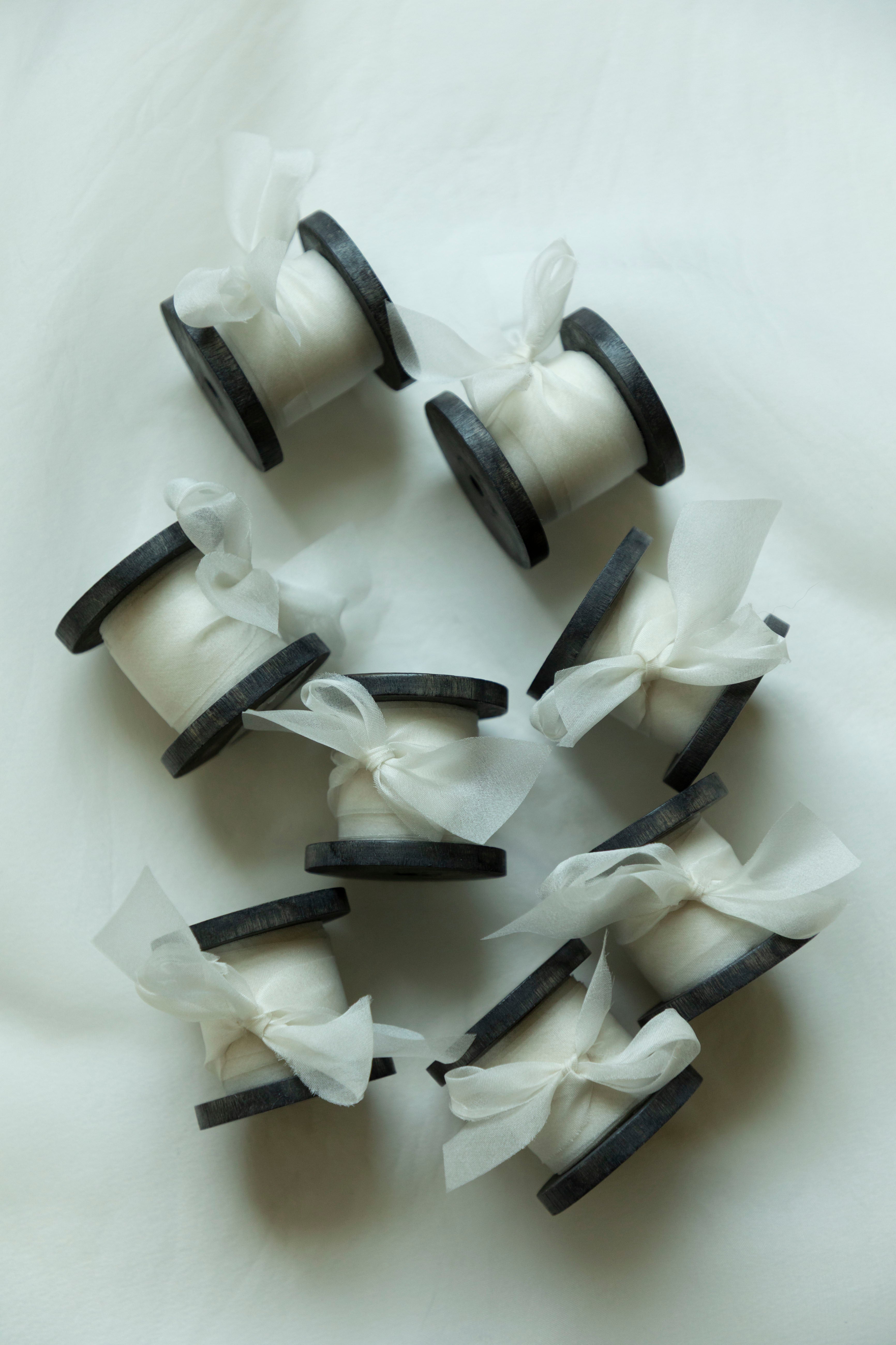 antique white organza silk ribbon on antique wood spool, displayed on white background