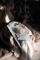 Decorative table setting with a napkin featuring butterfly design on a textured surface.