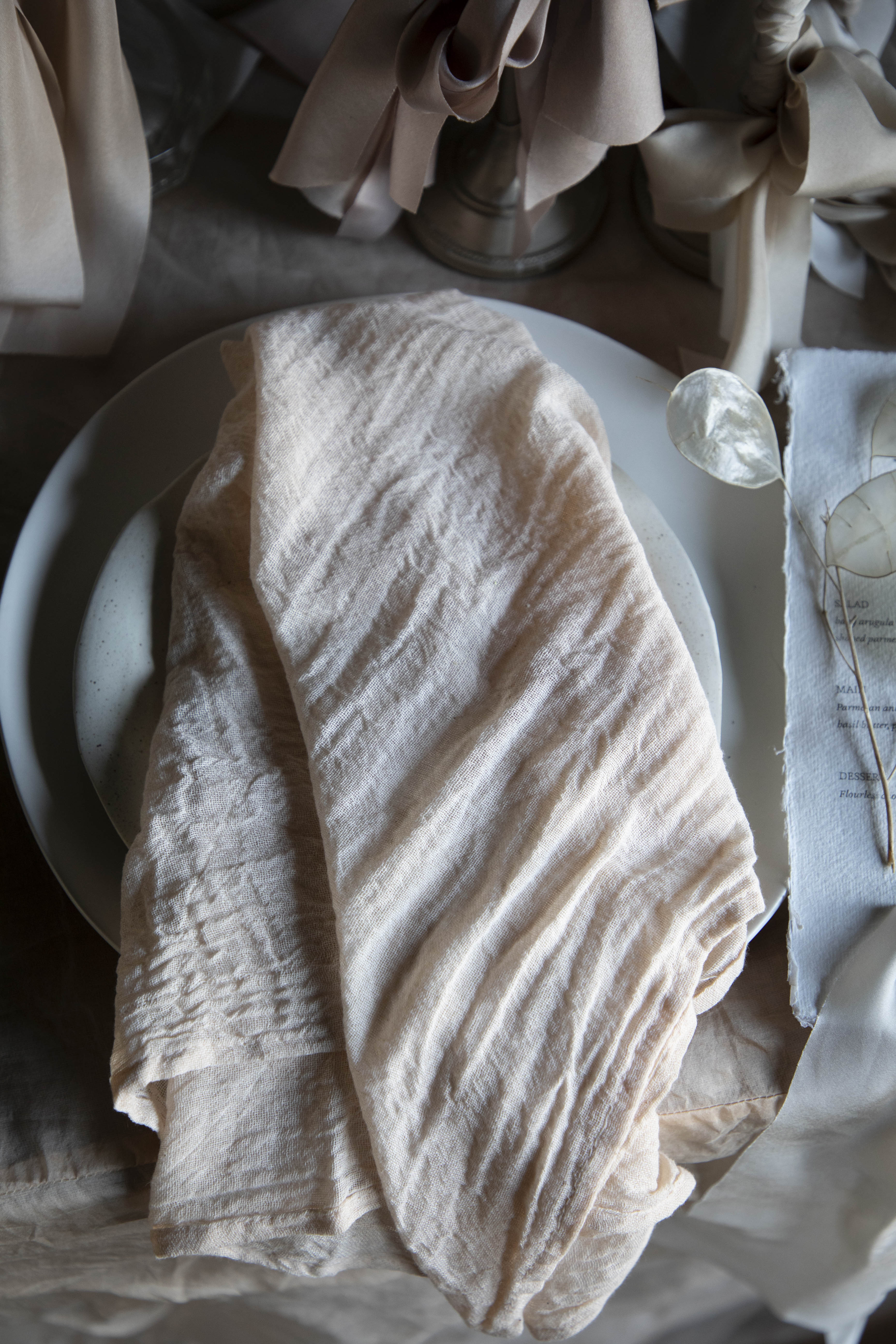 Neatly folded beige napkin on a white plate with a blurred background
