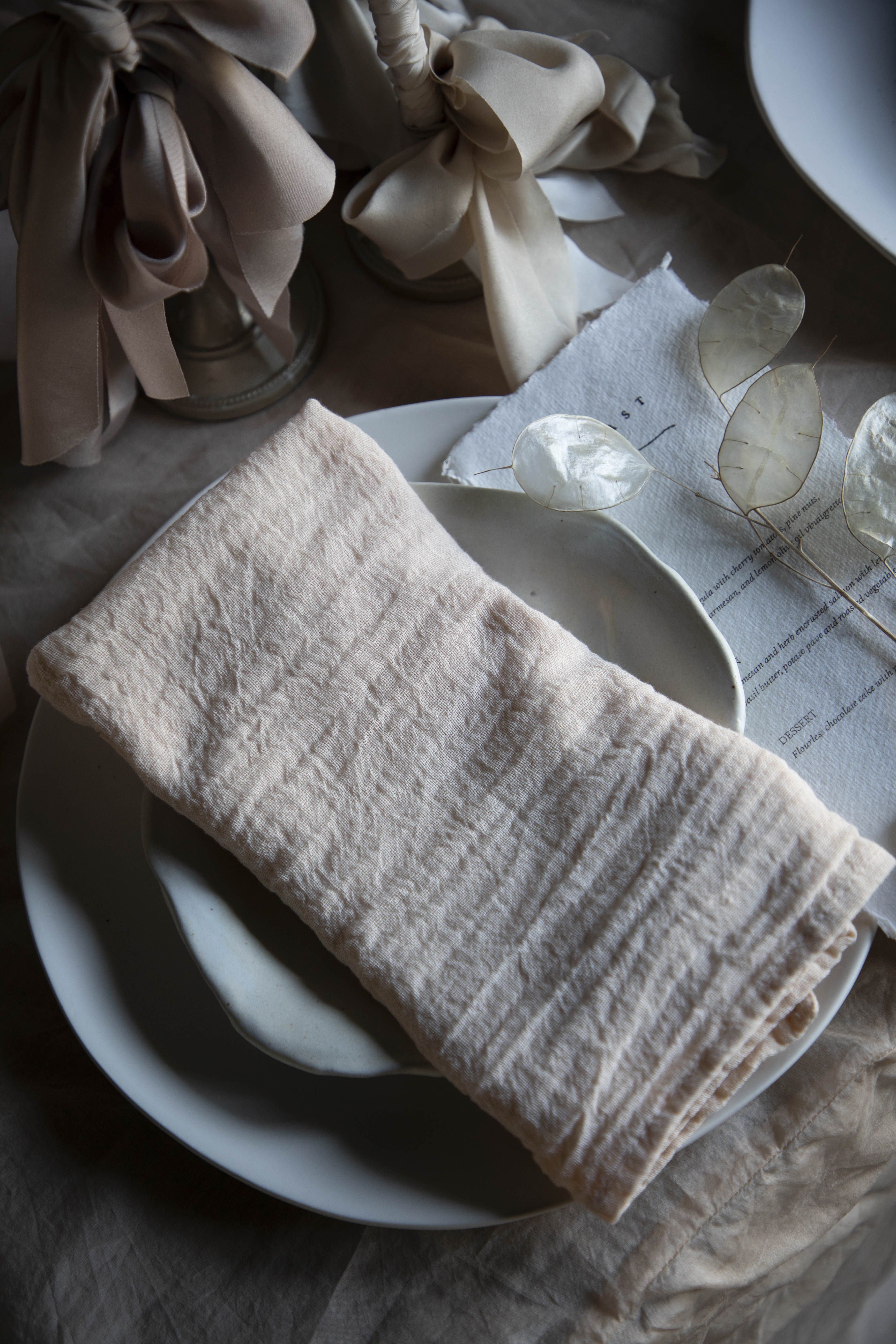 Folded blush napkin on a white plate with a textured surface