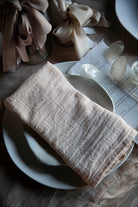 Folded blush napkin on a white plate with a textured surface