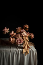 Bouquet of wedding flowers with a ribbon bow on a draped table with a black background