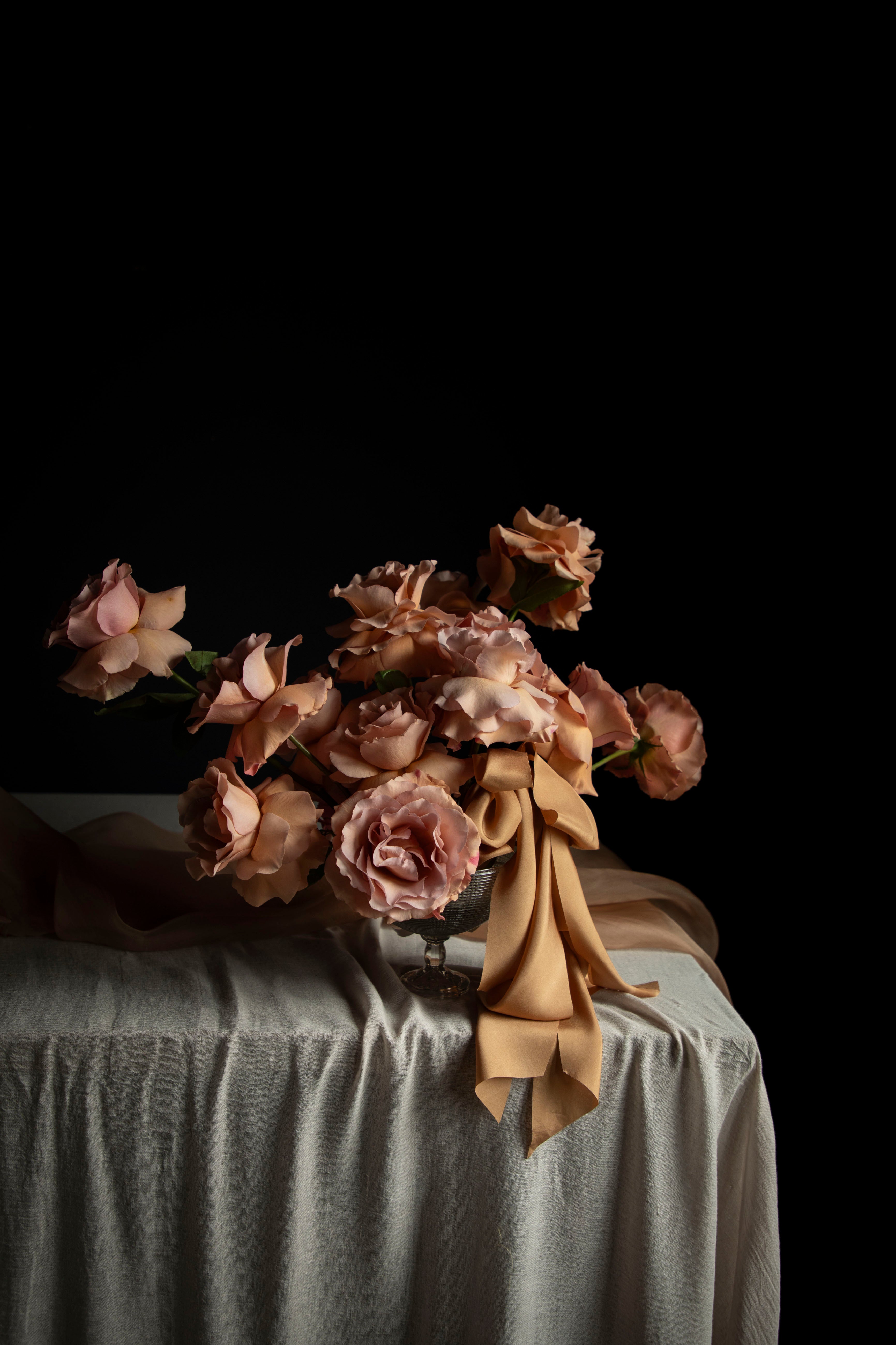 Bouquet of wedding flowers with a ribbon bow on a draped table with a black background
