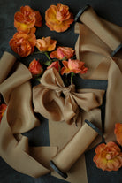 Cinnamon colored ribbons, and orange flowers on a dark background