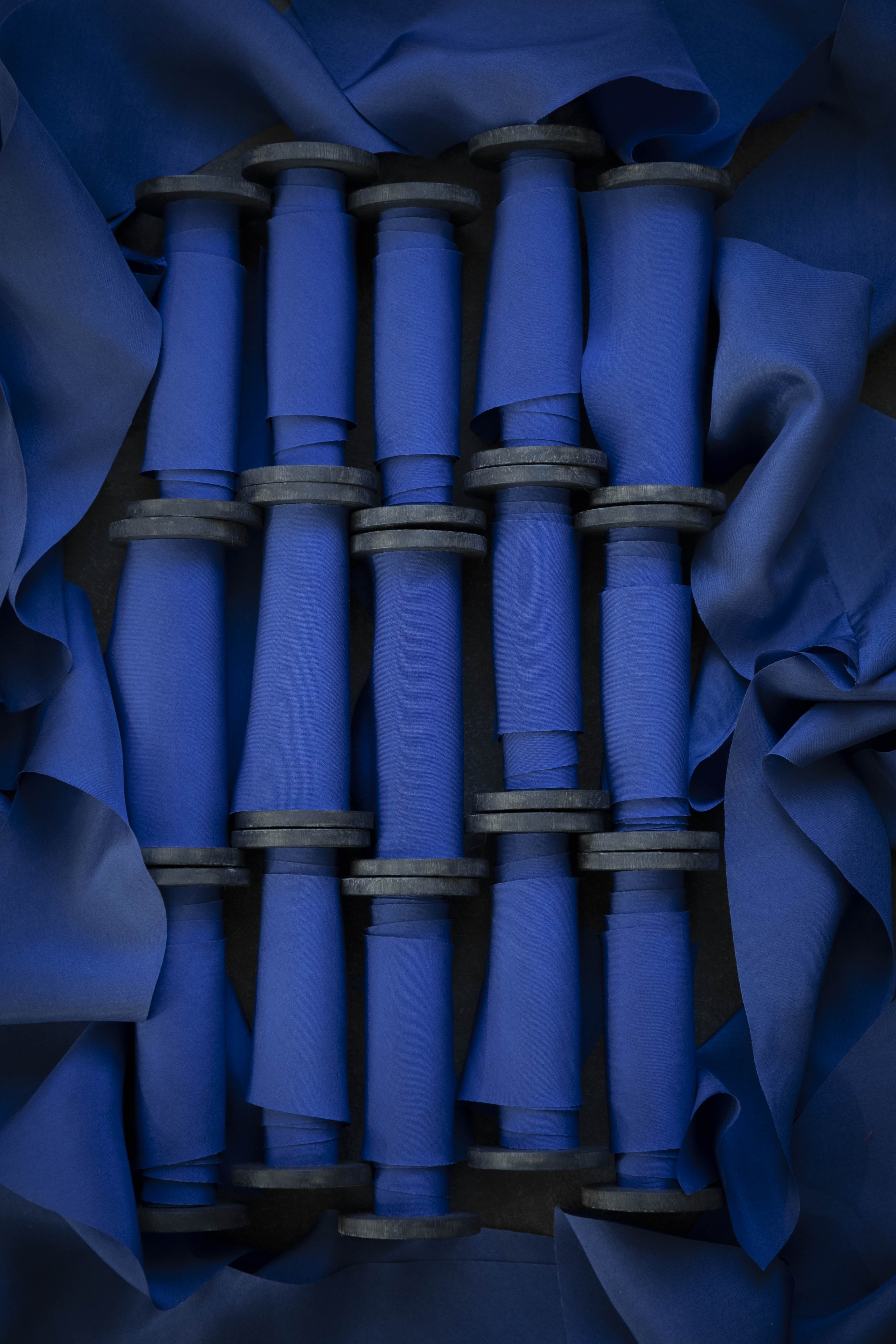 Blue fabric rolls stacked together with a dark blue background