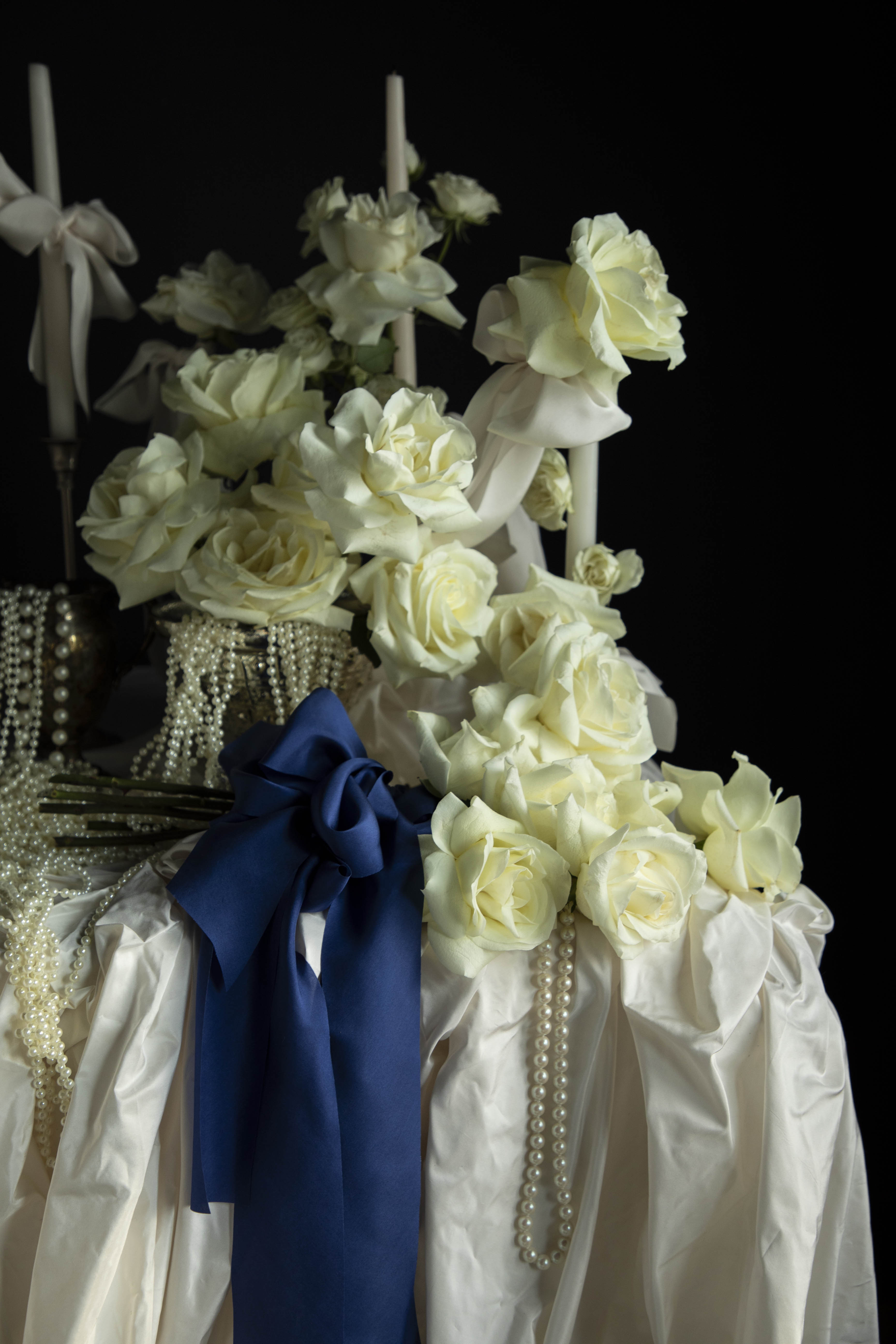 white roses and candles arrangement with draping pearls. bouquet of roses tied with cobalt silk ribbon.