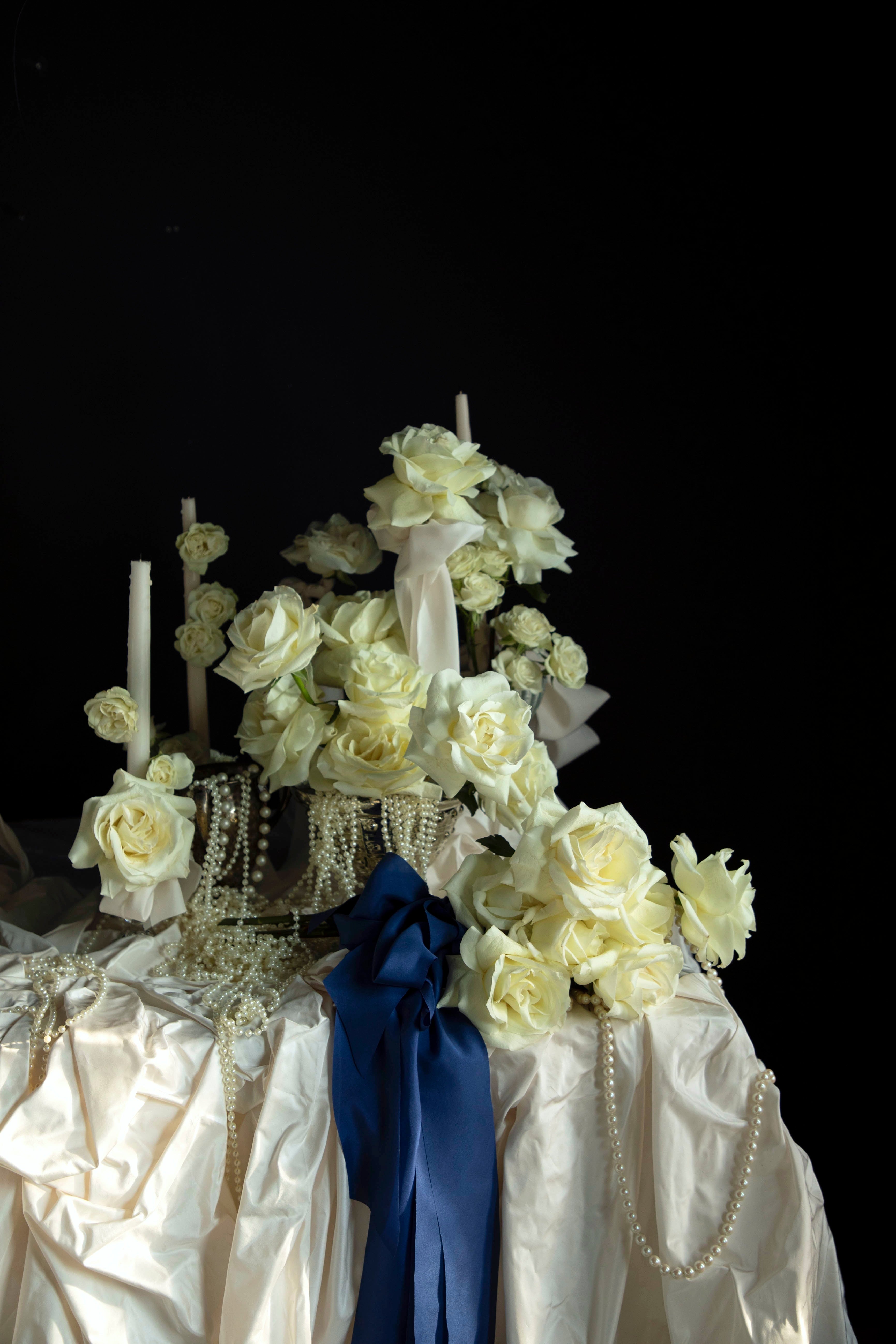 white roses and candles arrangement with draping pearls. bouquet of roses tied with cobalt silk ribbon.