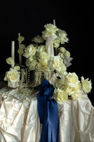 white roses and candles arrangement with draping pearls. bouquet of roses tied with cobalt silk ribbon.