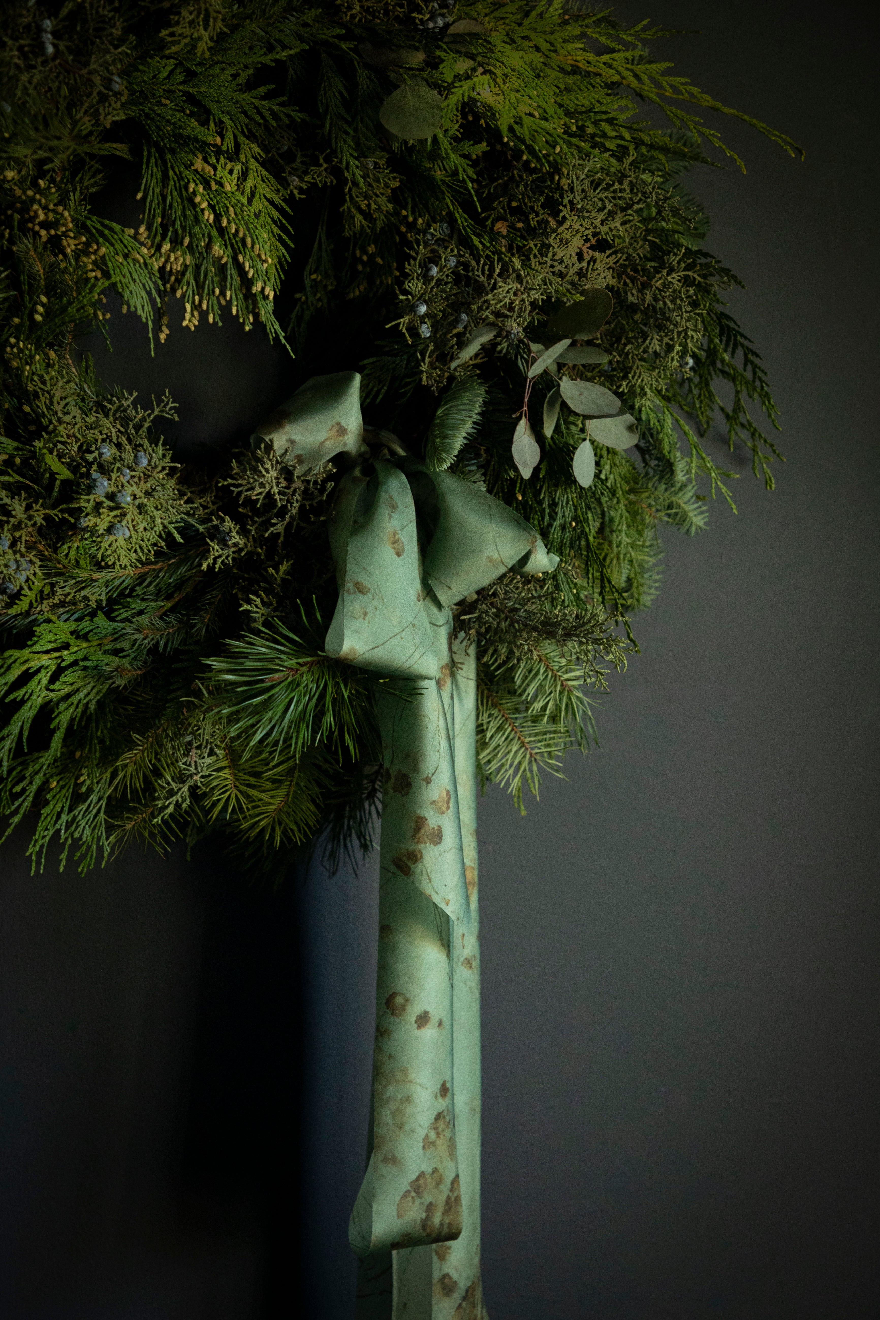 evergreen wreath for the holidays tied with silk ribbon bow. Eco-friendly silk ribbons with nature-inspired patterns, perfect for unique gift wrapping and tying market bouquets, crafted from sustainable materials