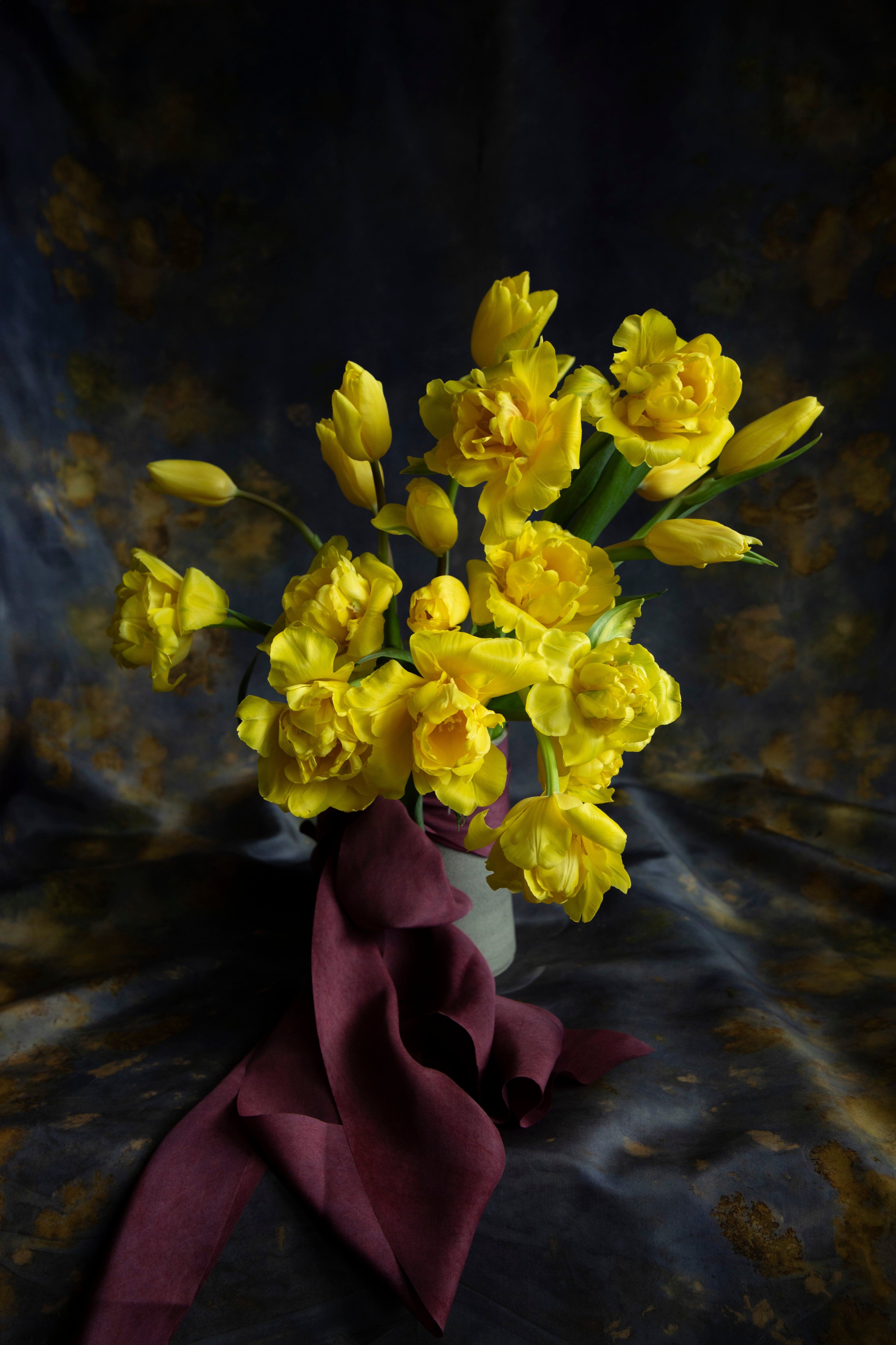 A bouquet of yellow flowers with a maroon, crushed berry silk ribbon.