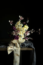 daffidols, magnolia branches, and tulip Bouquet in a vase on a dark background