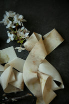 Ruffled silk ribbons with a small bouquet of white flowers on a dark surface