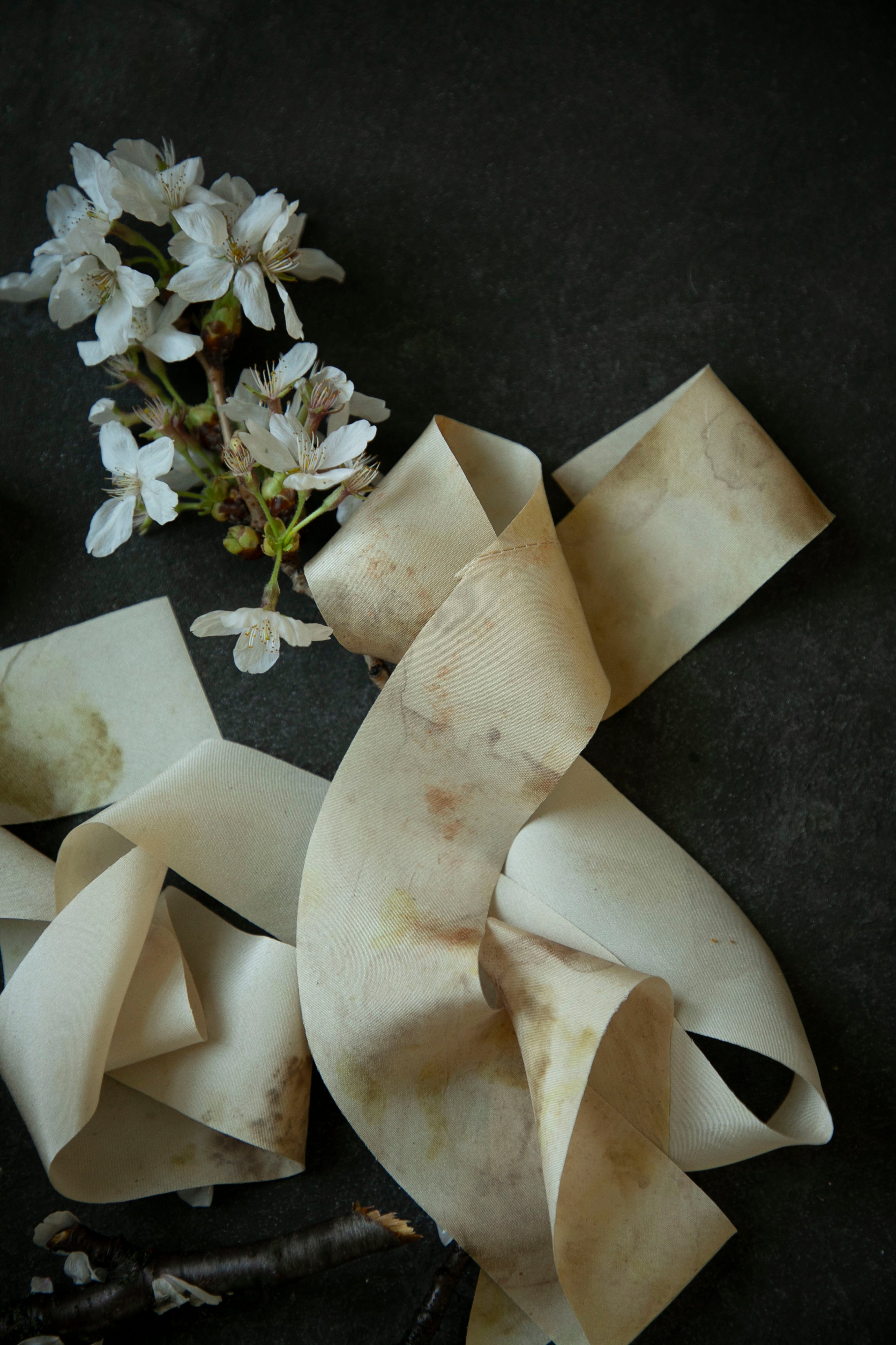 Ruffled silk ribbons with a small bouquet of white flowers on a dark surface