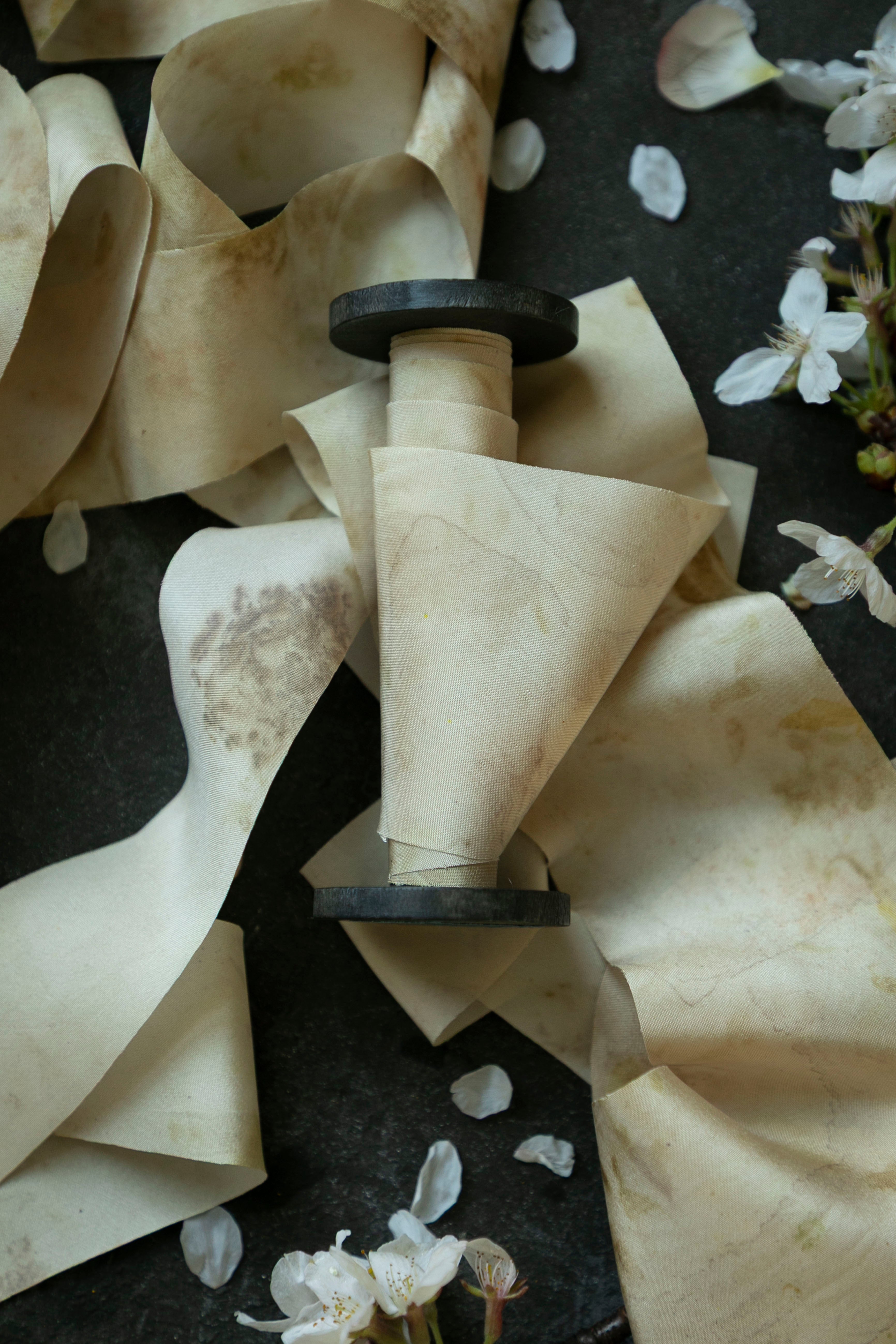 spool of the best silk ribbon on a dark surface with white flowers.