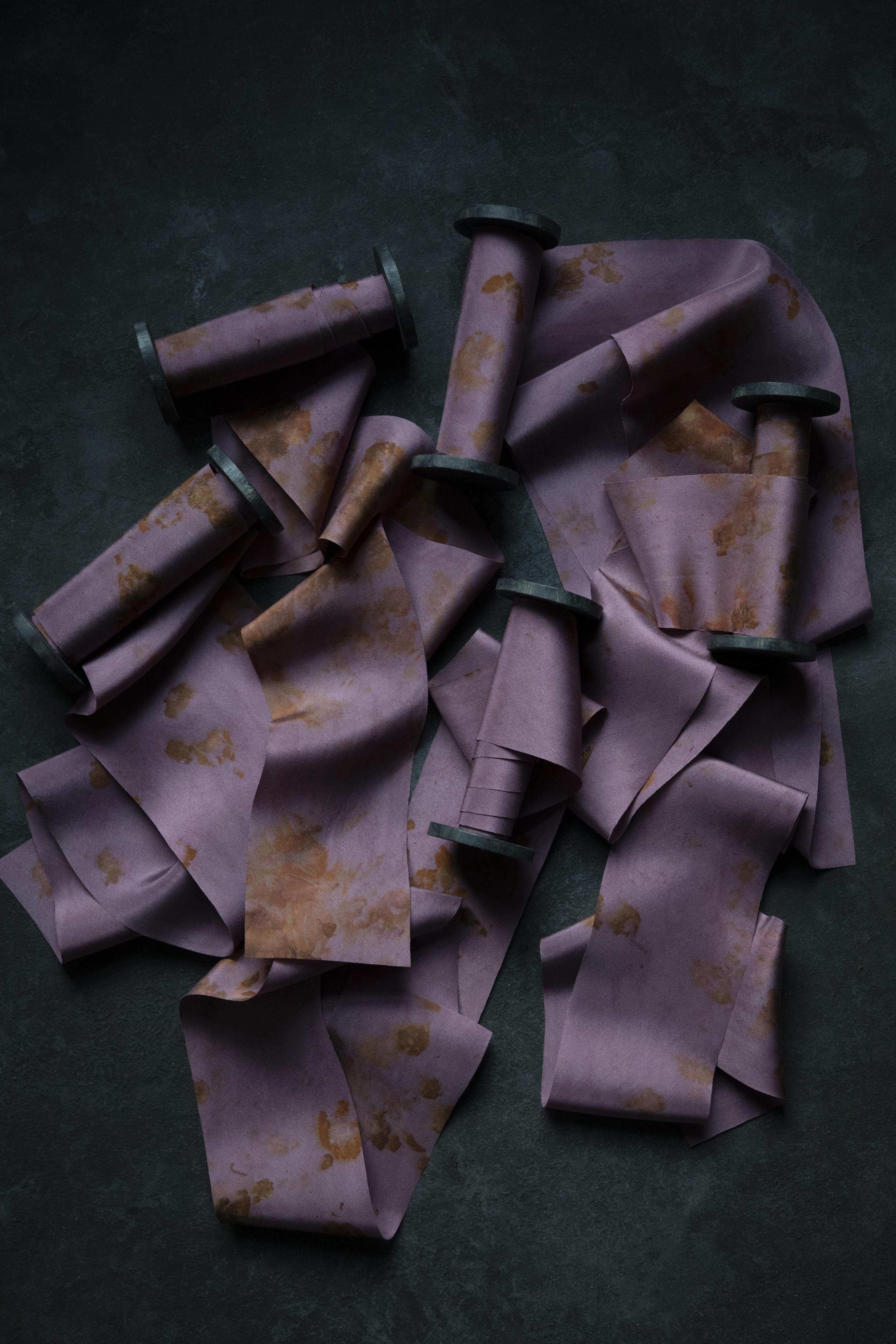 Purple ribbons with gold patterns scattered on a dark surface