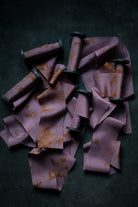 Purple ribbons with gold patterns scattered on a dark surface