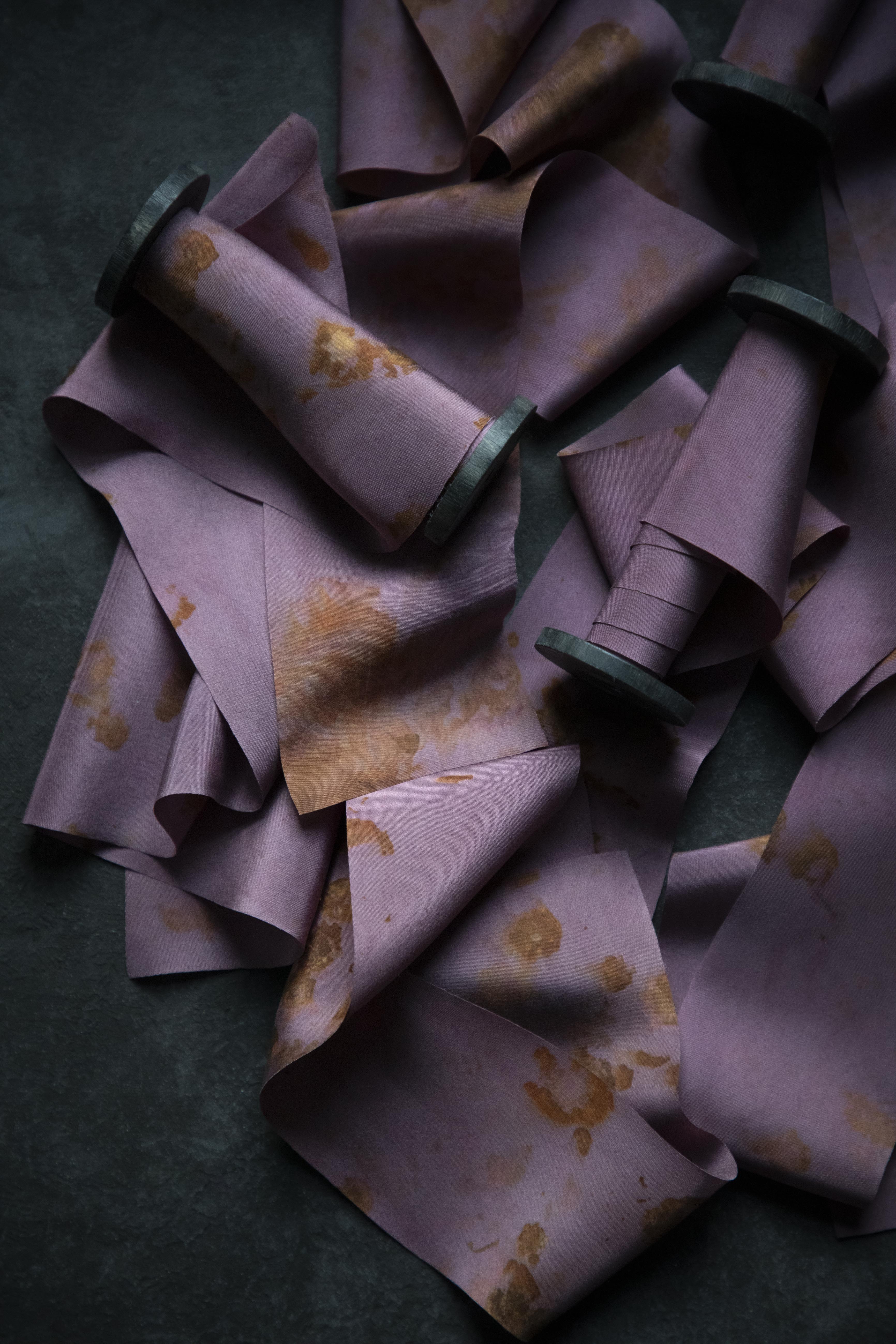 Purple fabric with brown spots on a dark green background