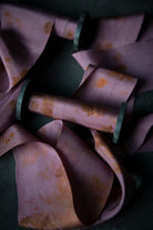 Close-up of a purple fabric with rust-colored stains on a dark background