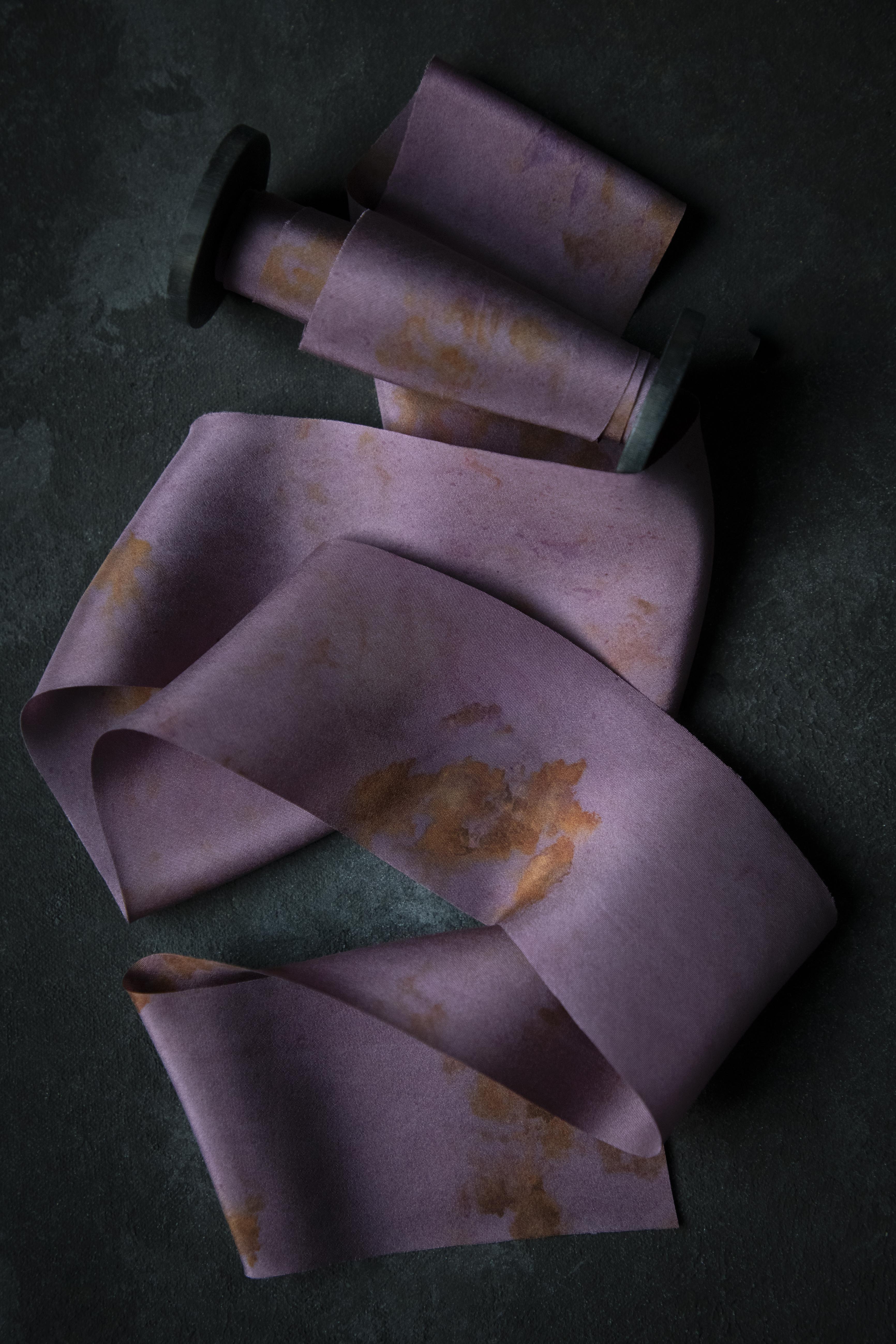 Purple fabric with yellow eco-prints on a dark surface