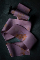 Purple fabric with yellow eco-prints on a dark surface