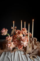 Decorative setup with flowers, candles, and ribbons on a dark background