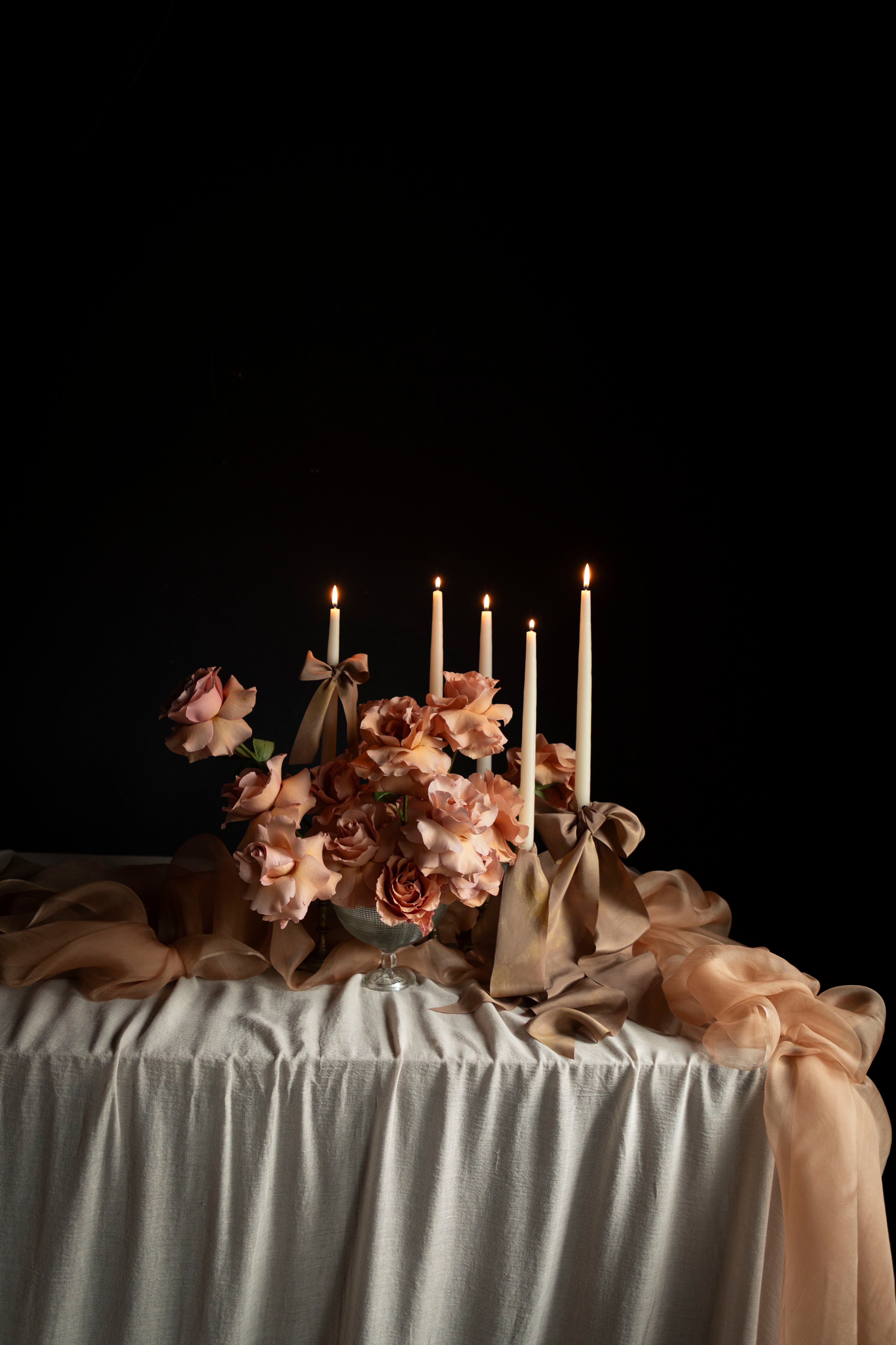 Decorative table setting with flowers, candles, and a dark background