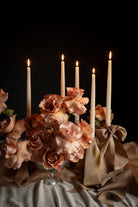 Candlelit scene with flowers and draped fabric against a dark background