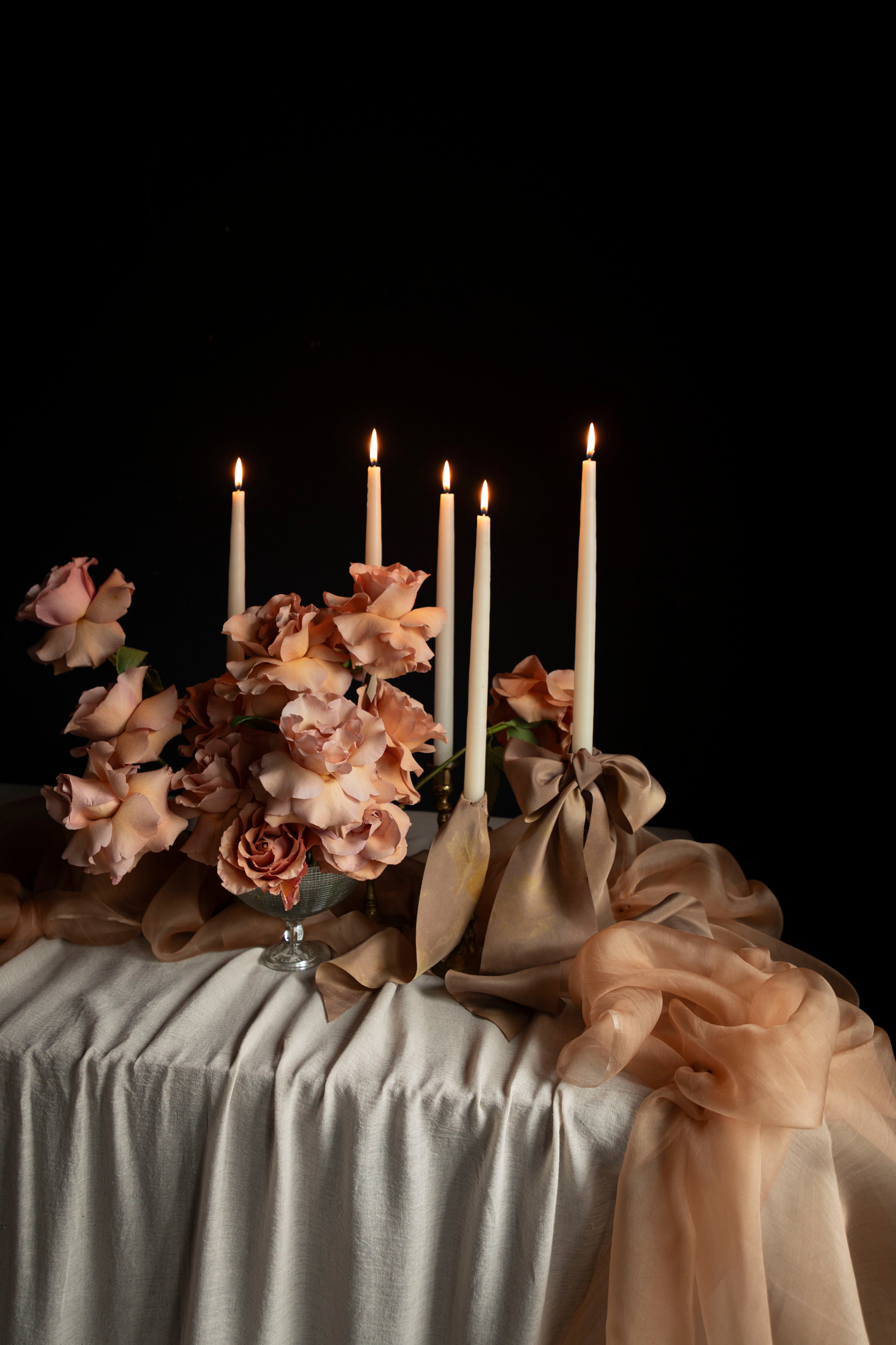 Decorative table setting with candles and flowers on a dark background