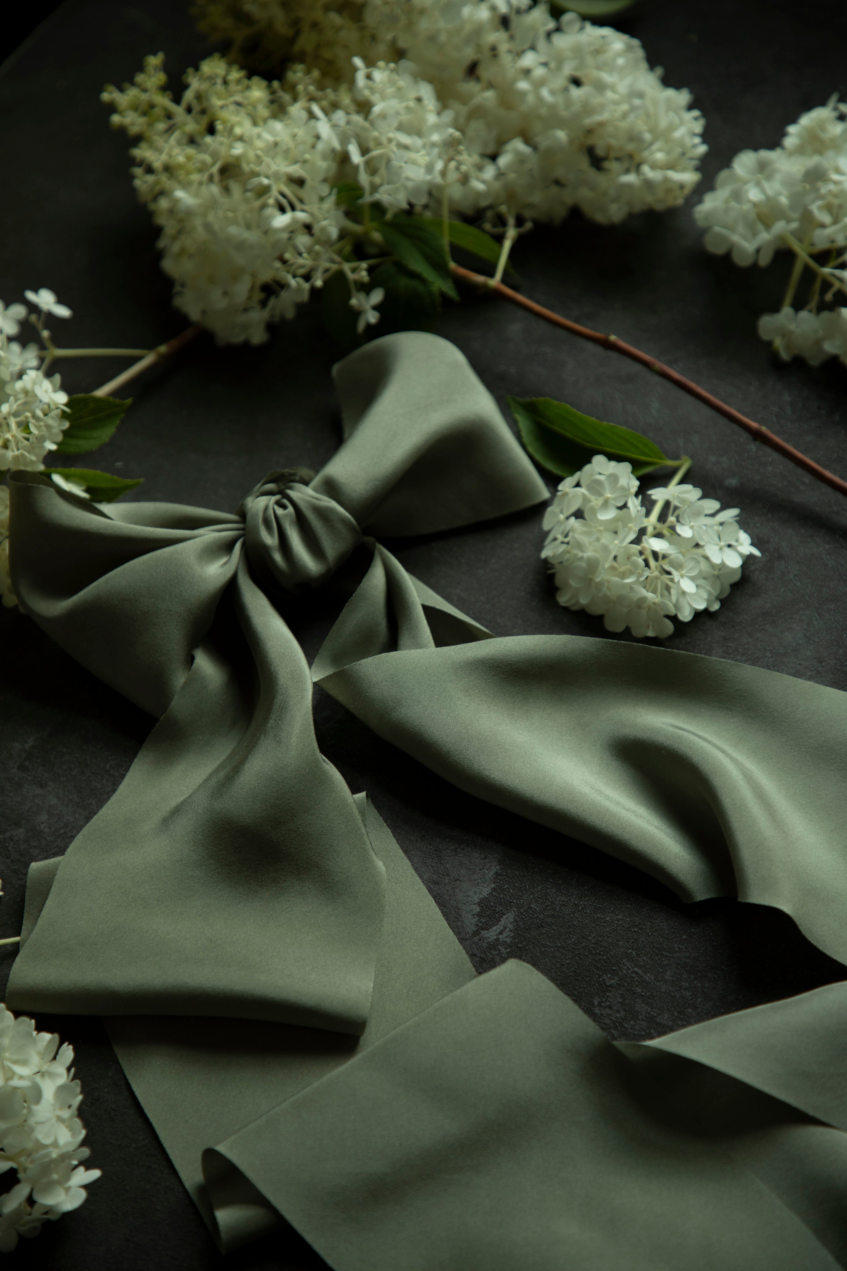 Green fabric with a bow and white flowers on a dark surface