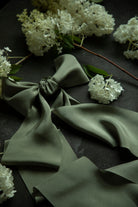 Green fabric with a bow and white flowers on a dark surface