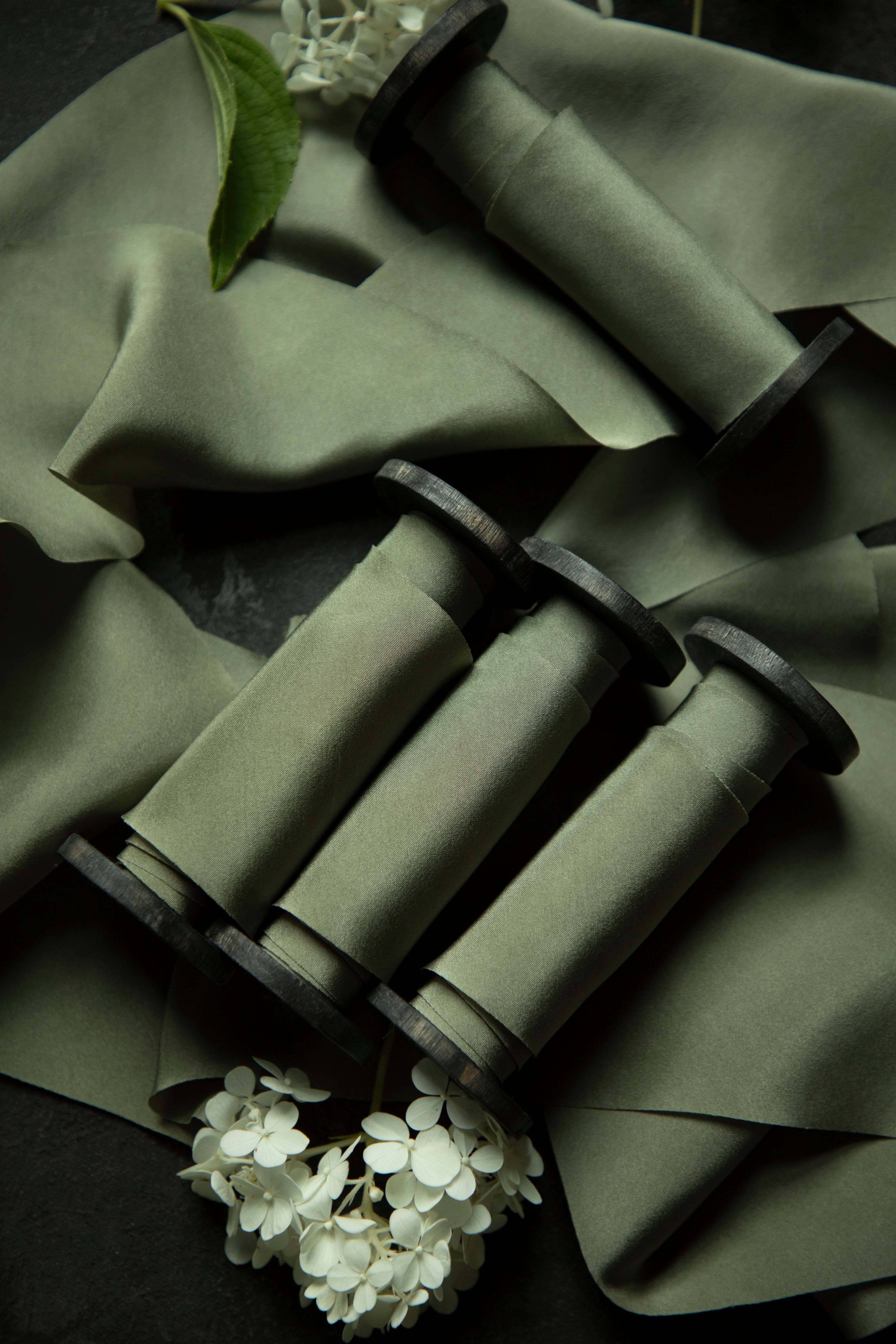 Green fabric with rolled-up items and white flowers on a dark background