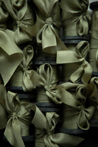 Stack of green silk ribbons on vintage style wood spools items with ribbons on a dark background