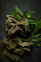 Gift wrapping inspiration with green ribbon with a bow on a gift box and leaves on a dark background