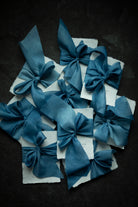 Indigo dyed Blue ribbon bows on white paper against a dark background