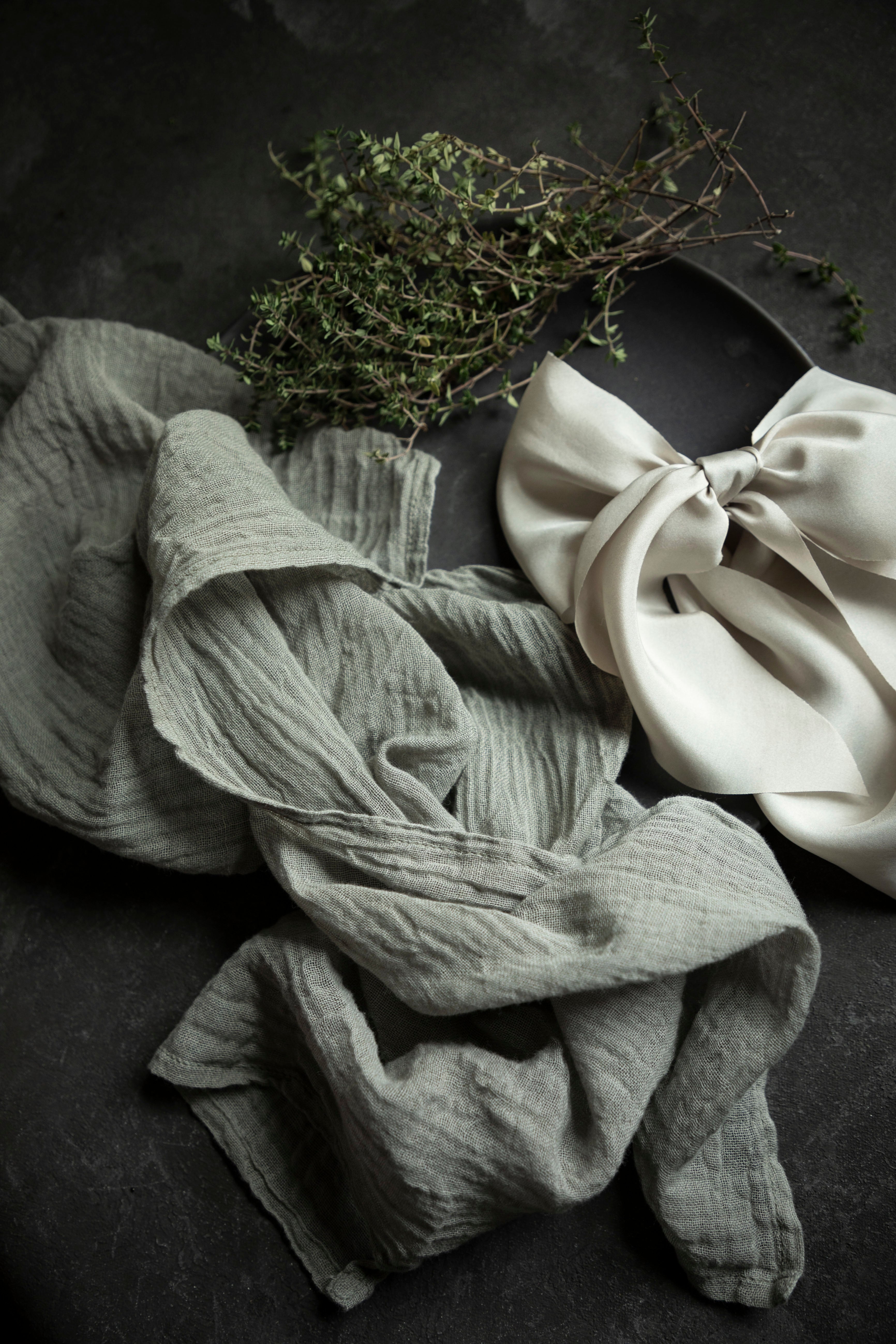 Folded napkin in gray and white on a dark surface with greenery.