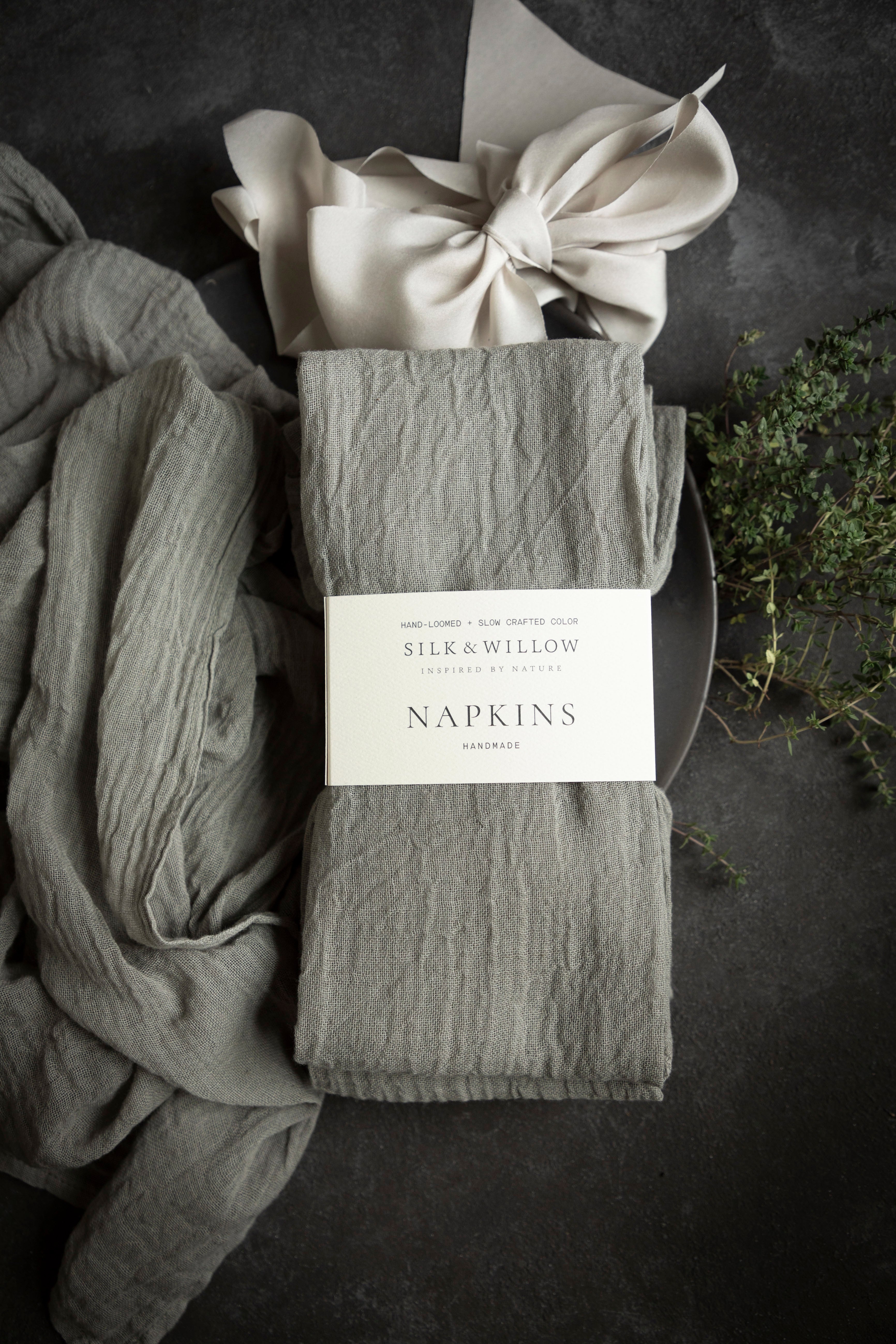 Packaged gray napkins with a bow on a dark surface, featuring the brand 'Silk & Willow'.