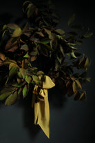 Bouquet of dried leaves with a yellow ribbon on a dark background